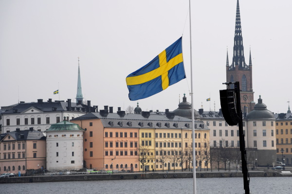 The economic and political development of Sweden Political development: An image of the Swedish flag in front of a limestone coloured building